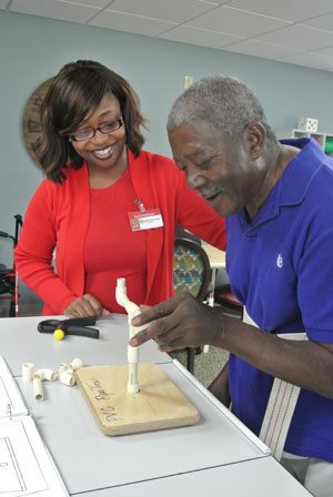 caregiver watyching elderly resident working on a project